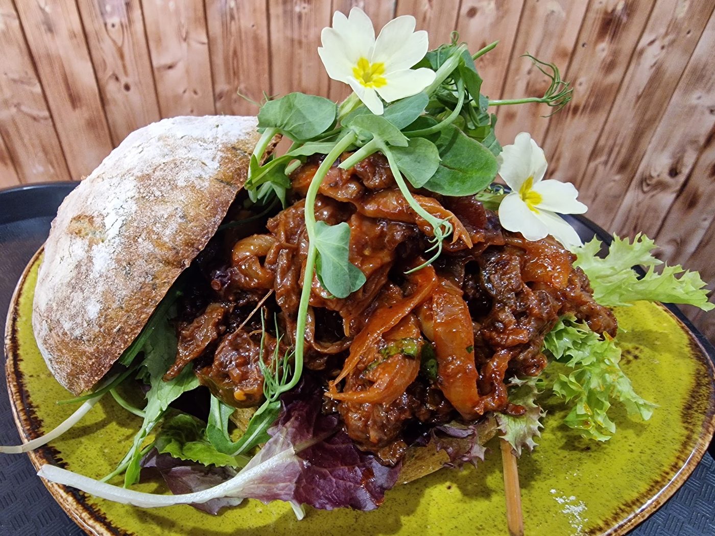 A crusty roll with meat and salad on a green plate